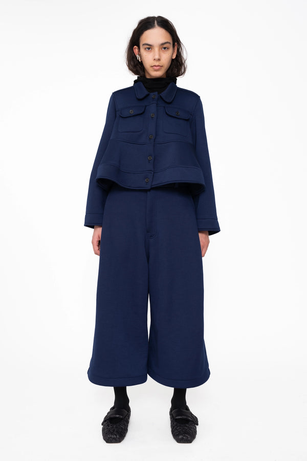 female-wearing-navy-cropped-jacket-with-wavy-hem-and-navy-cropped-wide-leg-culottes-on-white-background-full-body-front