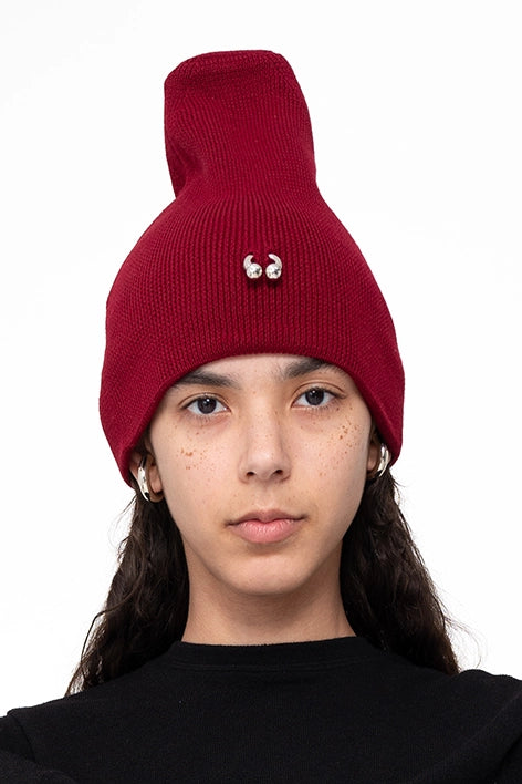female-wearing-bordeaux-pierced-beanie-with-etended-top-on-white-background-face-closeup