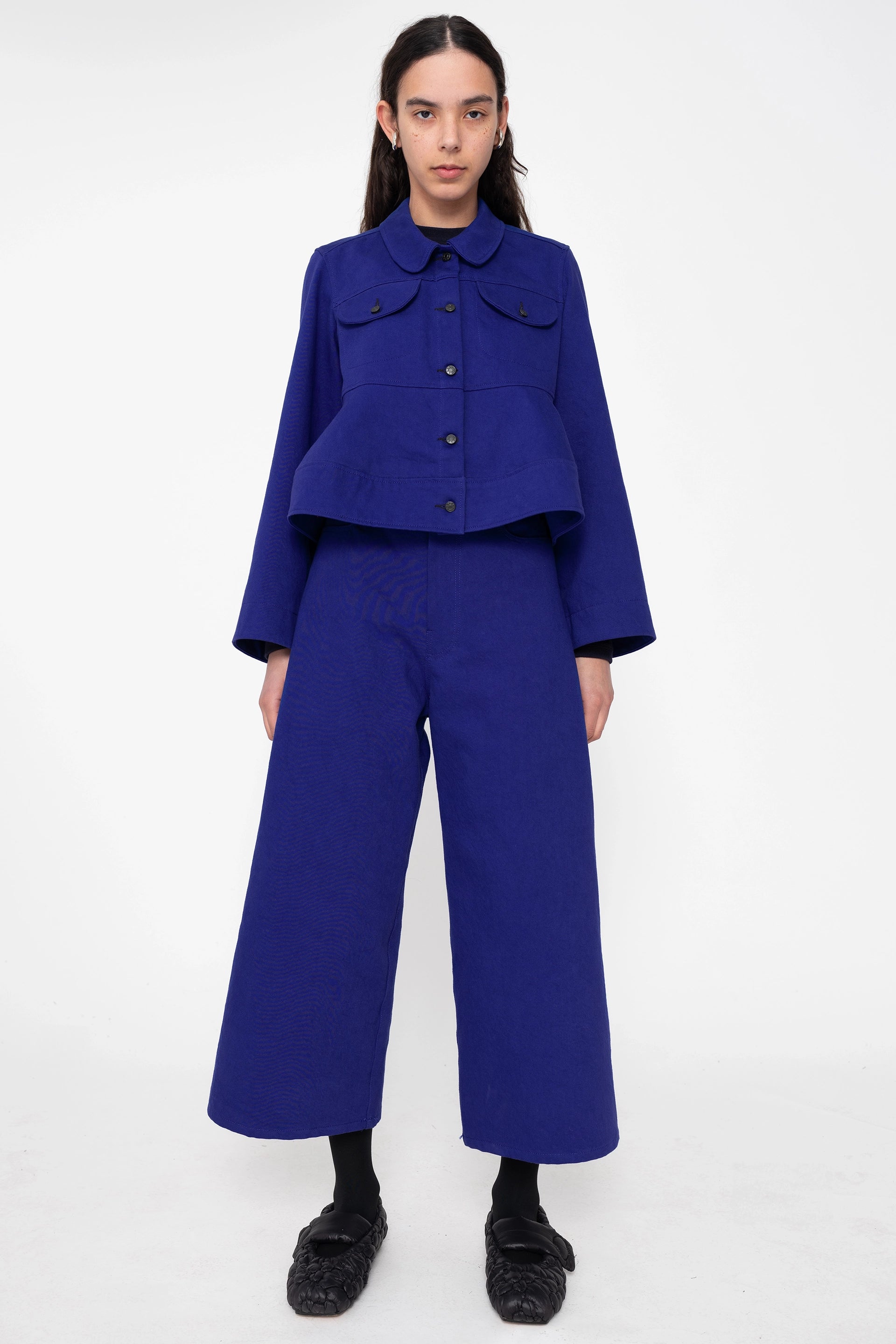 female-wearing-deep-blue-cropped-denim-jacket-with-wavy-hem-and-blue-denim-pants-full-body-front
