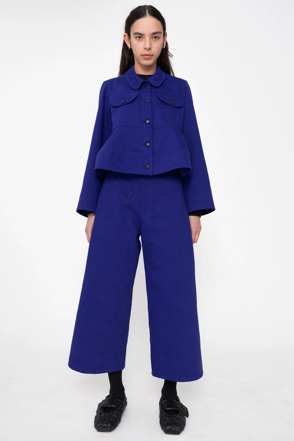 female-wearing-deep-blue-cropped-denim-jacket-with-wavy-hem-and-blue-denim-pants-full-body-front