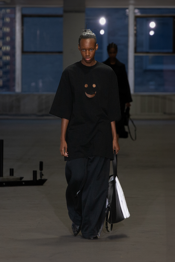 MODEL-WALKING-RUNWAY-INDUSTRIAL-SPACE-BIG-TEE-SHIRT-SMILE-FACE-CUT-OUT-BLACK-PANTS