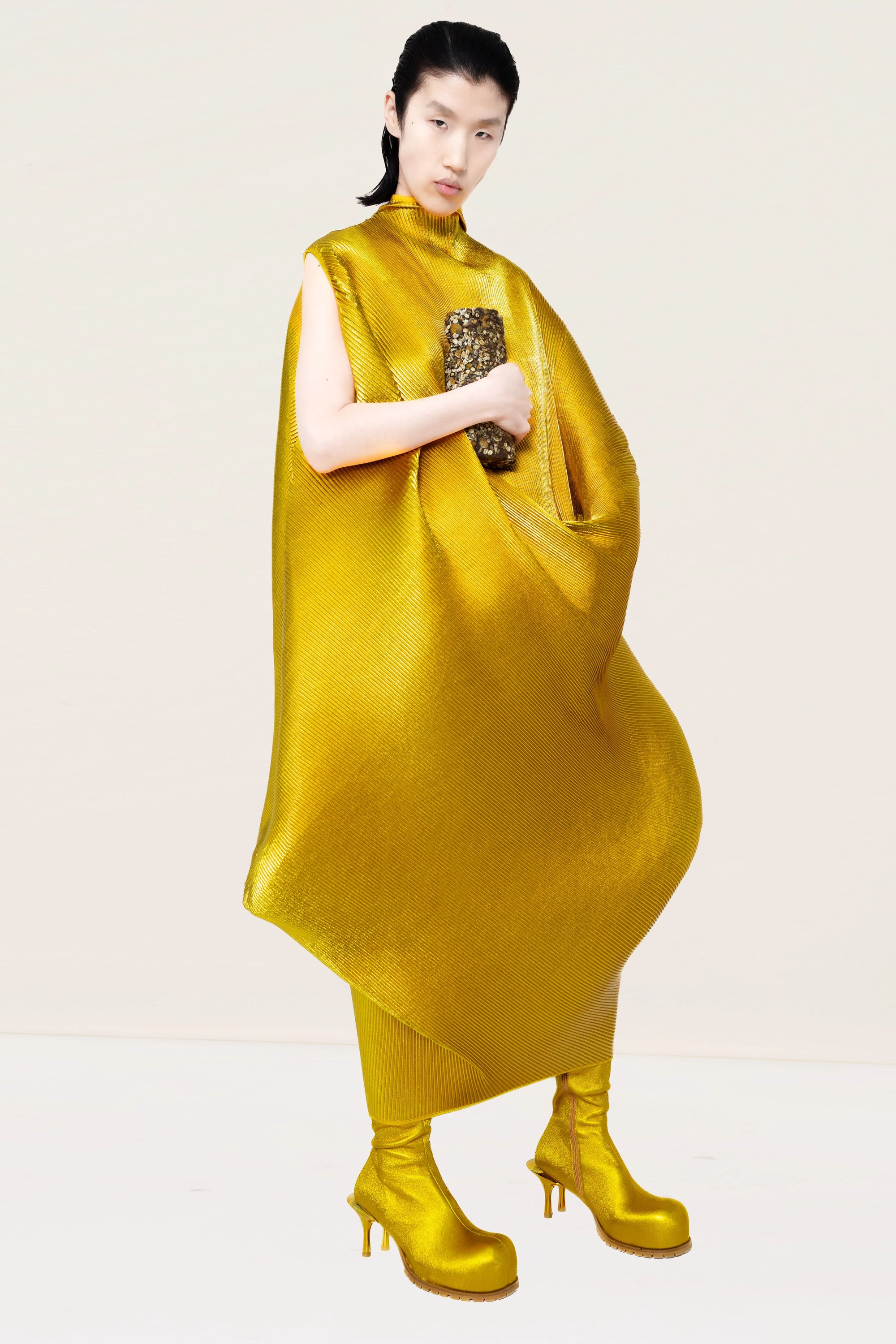 PERSON-WEARING-GOLD-RIPPLE-PLEAT-DRESS-WITH-STATUESQUE-SHAPE-WITH-MATCHING-GOLD-COWHIDE-DOUBLE-HEELED-BOOTS-HOLDING-LOAF-OF-BREAD-THREE-QUARTER-VIEW
