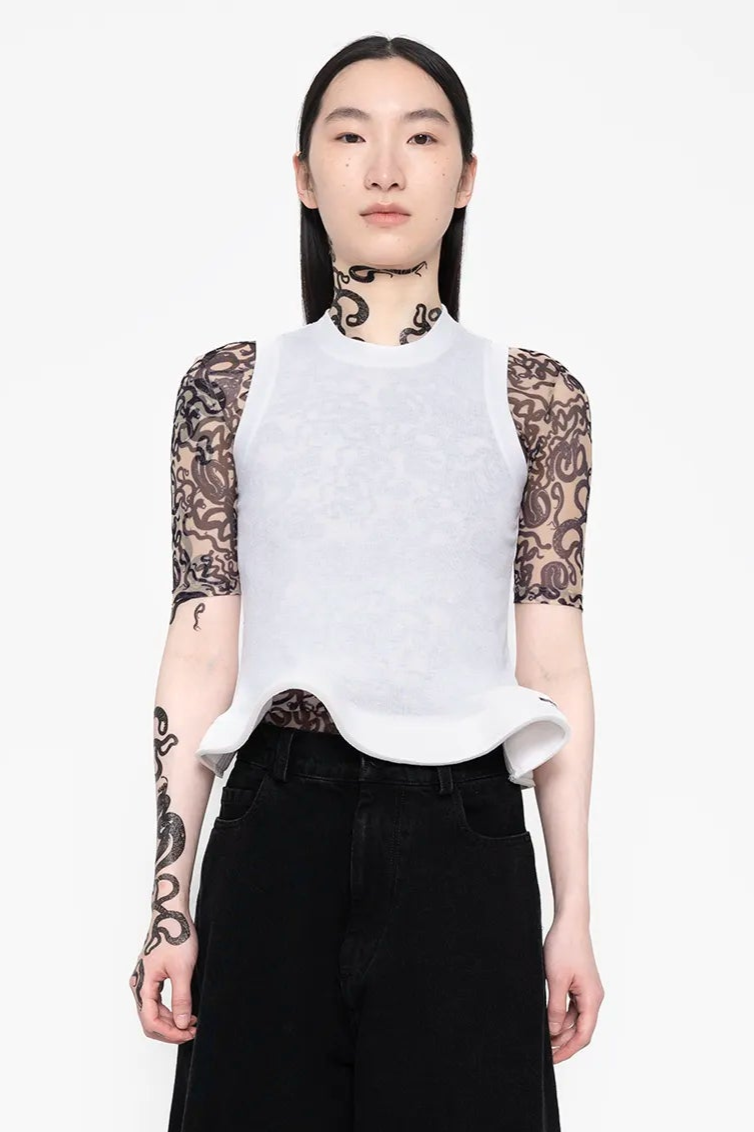 Person wearing a white top with lace sleeves and black pants on a white background
