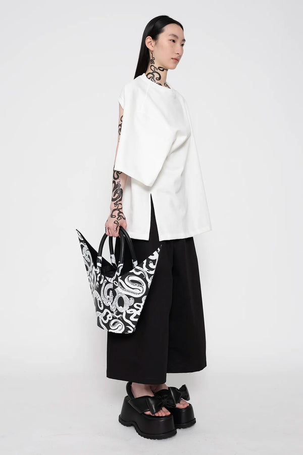 MELITTA-BAUMEISTER-Twisted-Tee-White-SLIGHT-RIGHT-SIDE-VIEW-WITHPOINTY-SHOULDER-BAG-WITH-WHITE-SNAKE-PRINT-IN-RIGHT-HAND