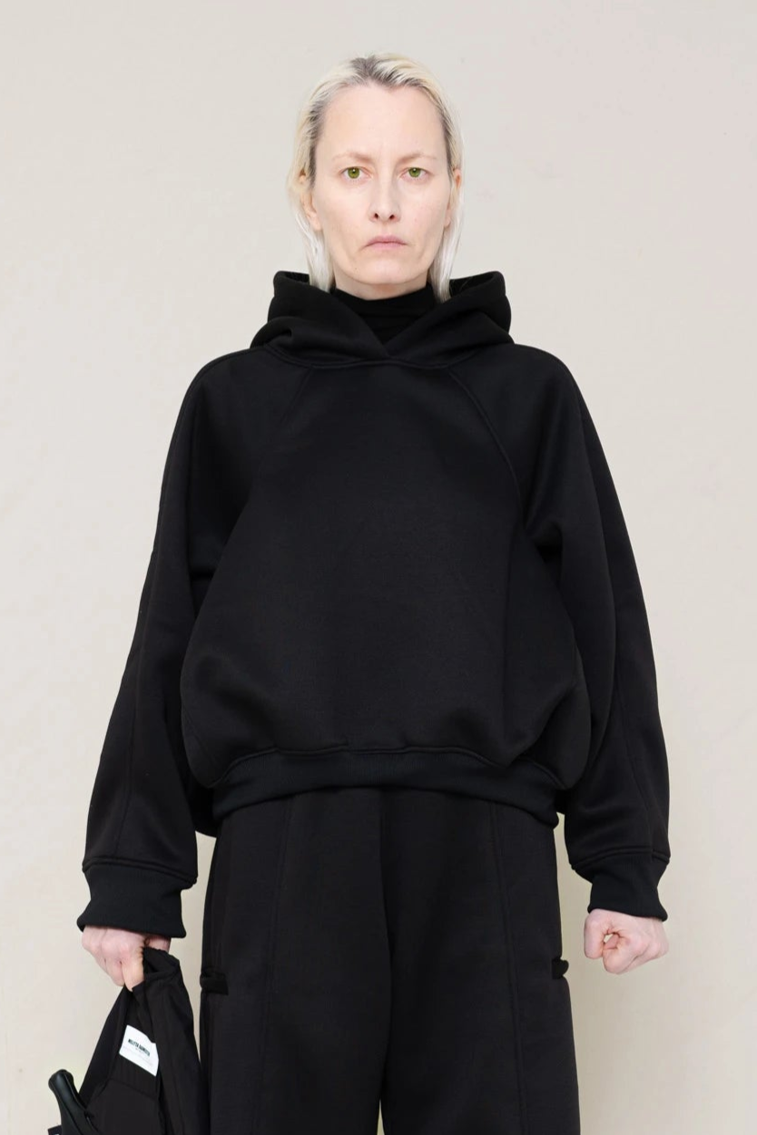 PERSON-WEARING-BLACK-CROPPED-HOODIE-WITH-MATCHING-BLACK-ROUND-LEG-LOUNGEPANTS-HOLDING-BLACK-BANANA-TOTE-BAG-CLOSE-UP-FRONT-VIEW