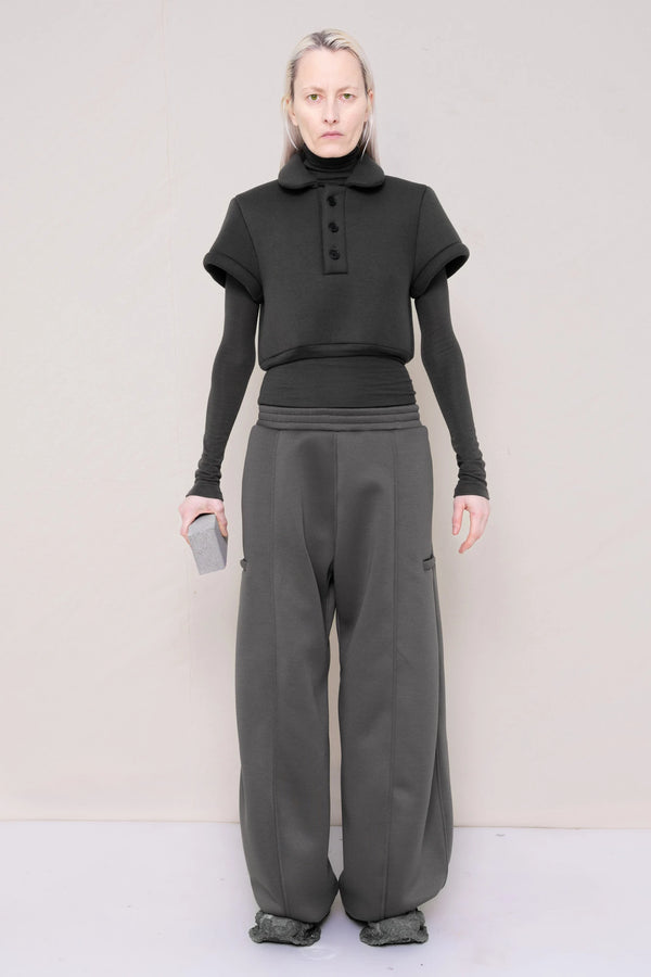 PERSON-WEARING-WARM-GREY-FOAMY-POLO-AND-LONGSLEEVE-TURTLENECK-WITH-STONE-GREY-ROUND-LEG-LOUNGEPANTS-AND-CUSTOMIZED-SNEAKERS-WHILE-HOLDING-GREY-BRICK-FRONT-VIEW