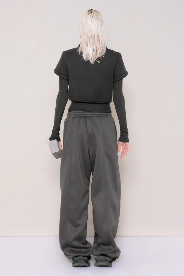PERSON-WEARING-WARM-GREY-FOAMY-POLO-AND-LONGSLEEVE-TURTLENECK-WITH-STONE-GREY-ROUND-LEG-LOUNGEPANTS-AND-CUSTOMIZED-SNEAKERS-WHILE-HOLDING-GREY-BRICK-BACK-VIEW