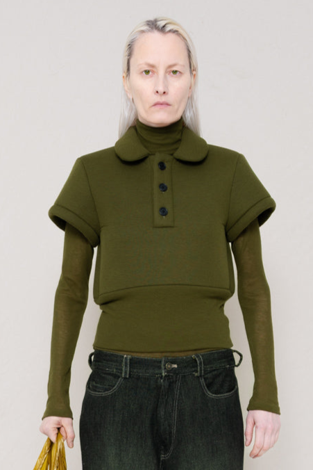 PERSON-WEARING-MOSS-FOAMY-POLO-WITH-MOSS-LONG-SLEEVE-TURTLENECK-UNDER-AND-BLACK-YELLOW-WASH-DENIM-PANTS-HOLDING-GOLD-TOTE-BAG-CLOSE-UP-FRONT-VIEW