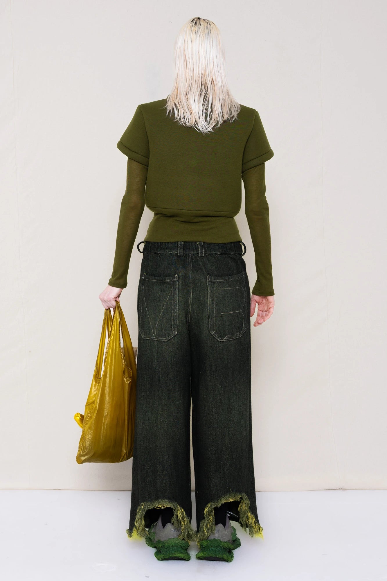 PERSON-WEARING-MOSS-FOAMY-POLO-WITH-MOSS-LONG-SLEEVE-TURTLENECK-UNDER-AND-BLACK-YELLOW-WASH-DENIM-PANTS-WITH-CUSTOMIZED-SNEAKERS-HOLDING-GOLD-BANANA-TOTE-BAG-BACK-VIEW