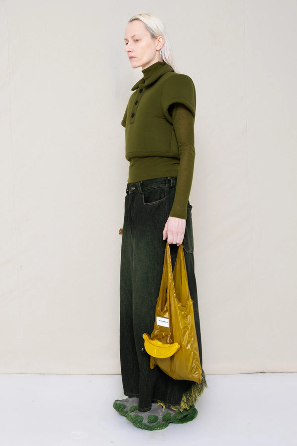PERSON-WEARING-MOSS-FOAMY-POLO-WITH-MOSS-LONG-SLEEVE-TURTLENECK-UNDER-AND-BLACK-YELLOW-WASH-DENIM-PANTS-WITH-CUSTOMIZED-SNEAKERS-HOLDING-GOLD-BANANA-TOTE-BAG-THREE-QUARTER-VIEW