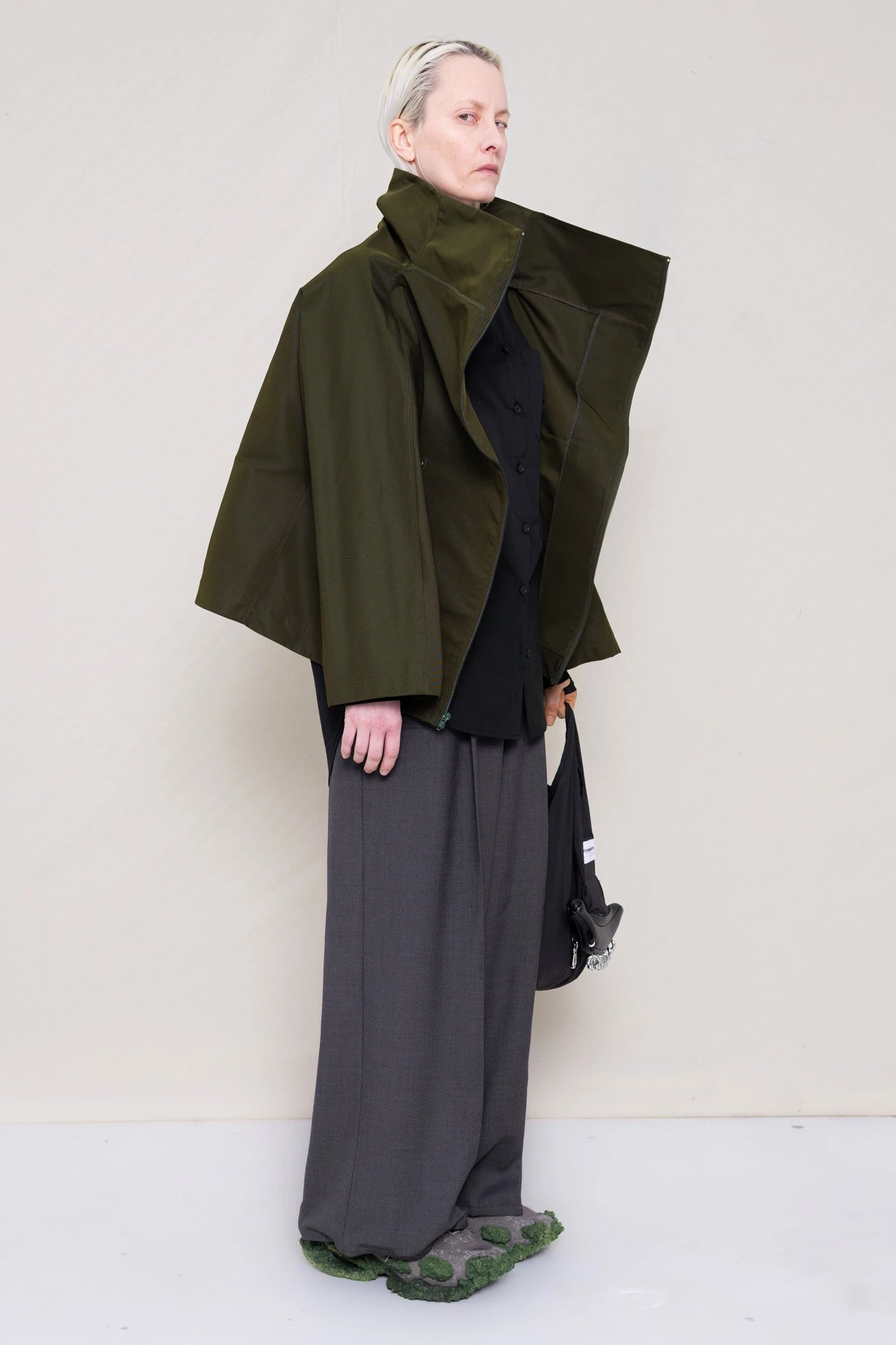 PERSON-WEARING-MOSS-BODY-ZIP-UP-JACKET-WITH-BLACK-BUTTON-DOWN-AND-GREY-TAILORED-PANTS-AND-CUSTOMIZED-SNEAKERS-THREE-QUARTER-VIEW