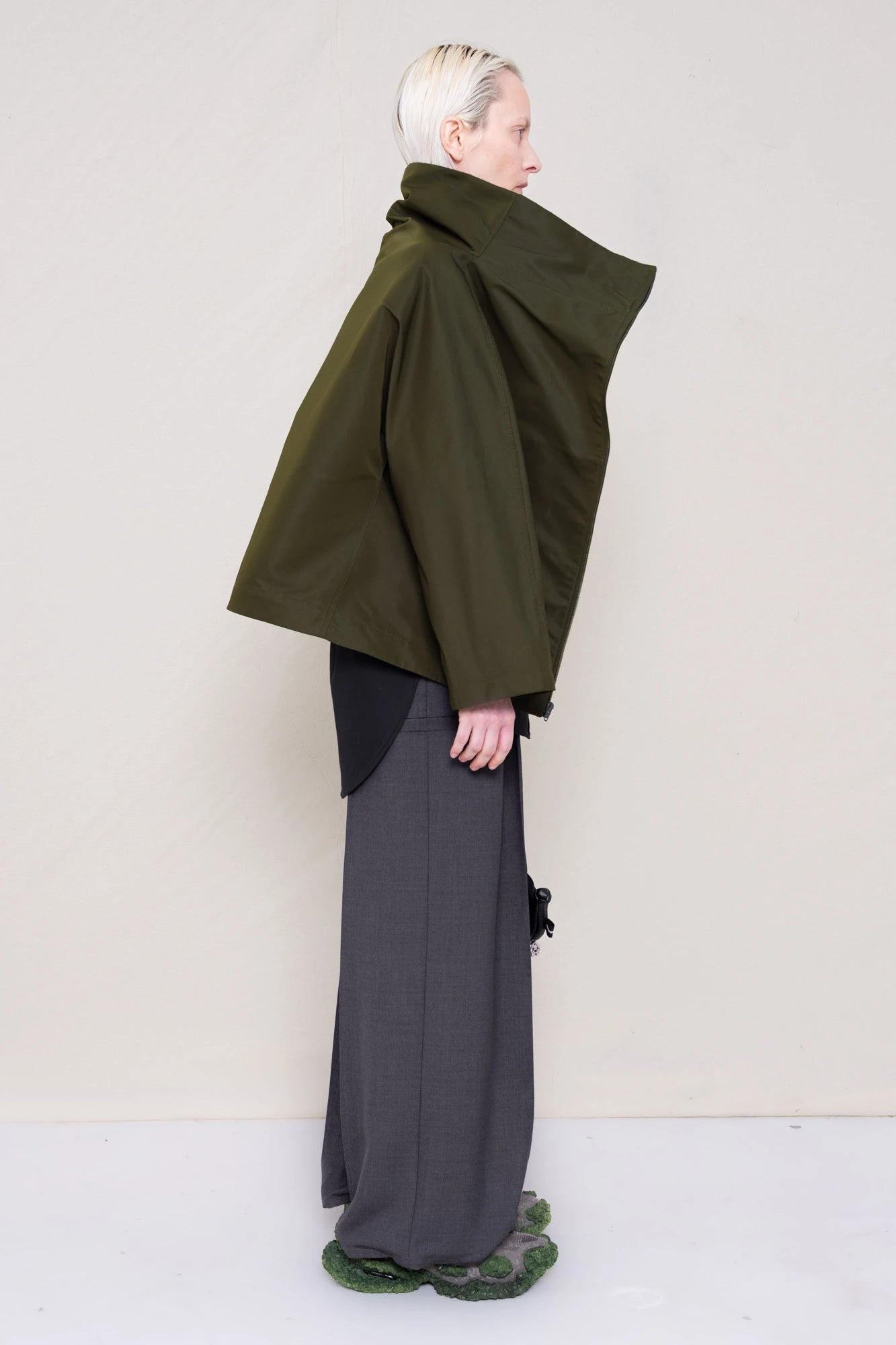 PERSON-WEARING-MOSS-BODY-ZIP-UP-JACKET-WITH-BLACK-BUTTON-DOWN-AND-GREY-TAILORED-PANTS-AND-CUSTOMIZED-SNEAKERS-SIDE-VIEW