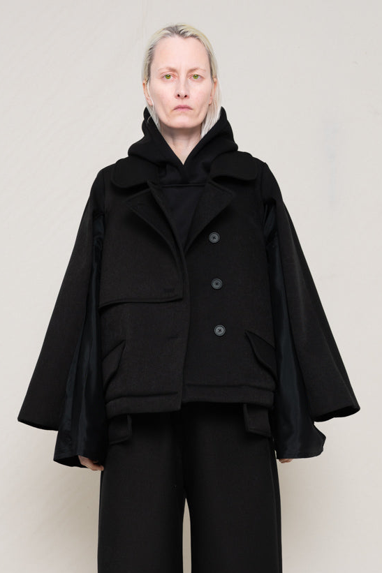 A-model-wearing-a-double-lapeled-black-jacket-with-a-silky-second-sleeve-paired-with-black-trousers-Front-view.