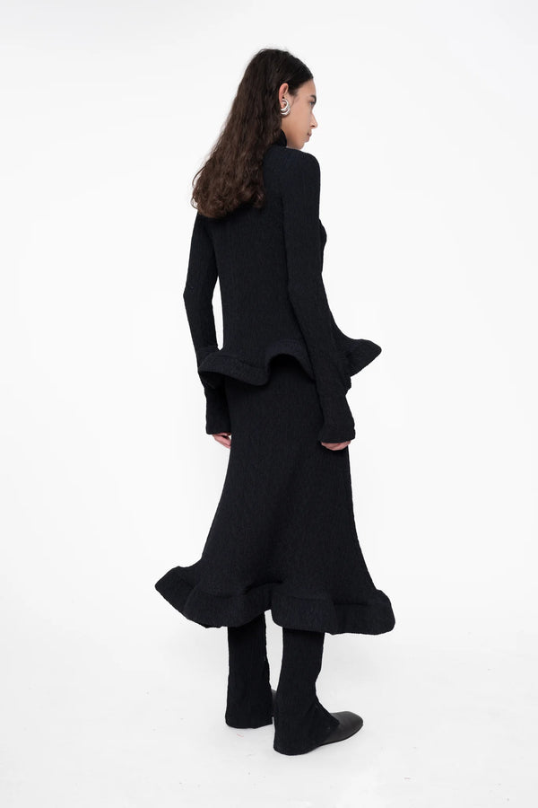 female-wearing-tight-black-longsleeve-turtleneck-top-with-wavy-hem-and-hole-in-sleeve-detail-on-white-background-full-body-back-side