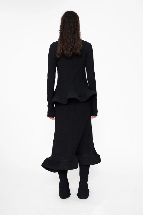 female-wearing-tight-black-longsleeve-turtleneck-top-with-wavy-hem-and-hole-in-sleeve-detail-on-white-background-full-body-back