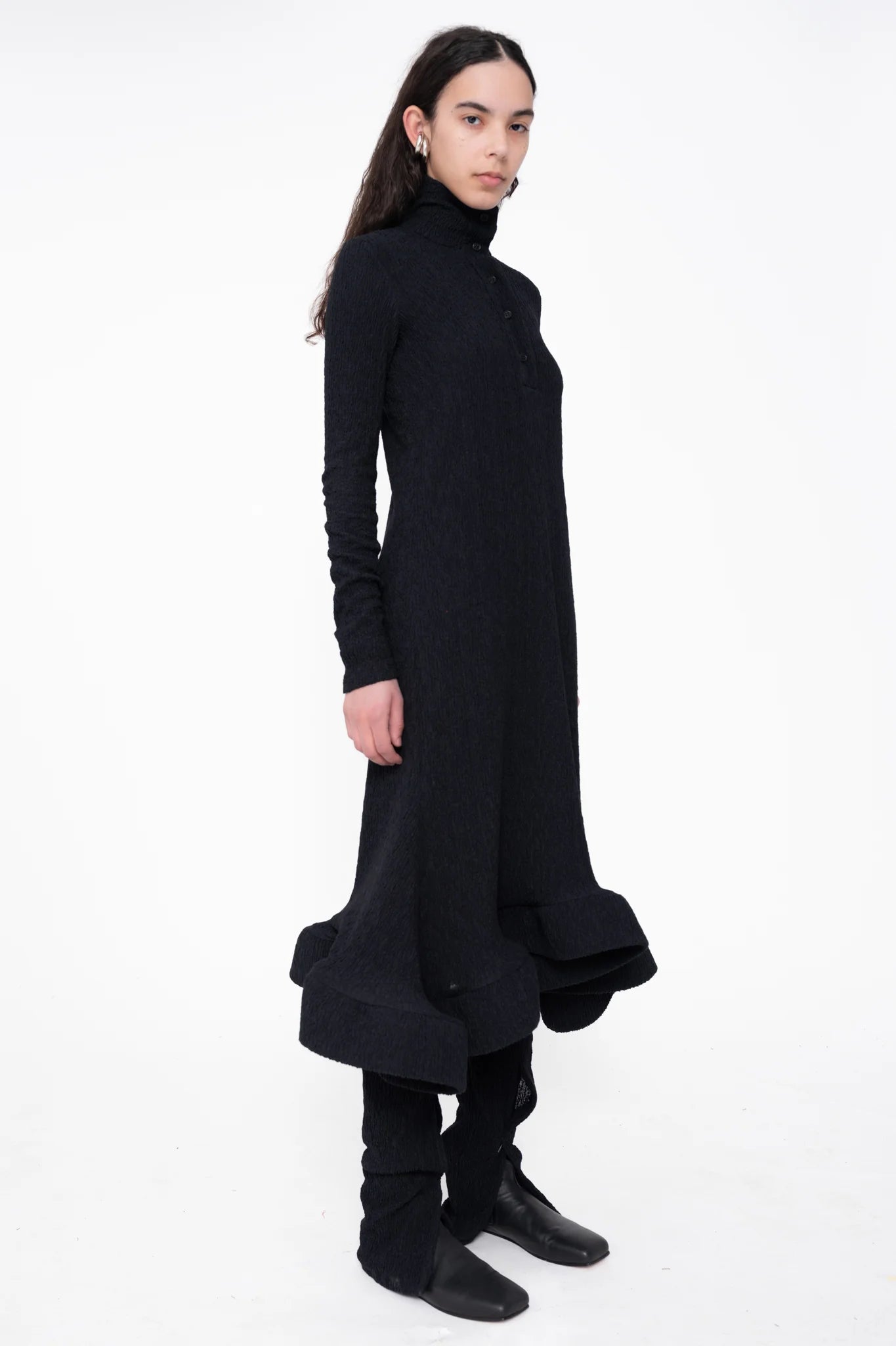 female-wearing-black-longsleeve-midi-dress-with-wavy-hem-and-button-closure-on-white-background-full-body-three-quarter