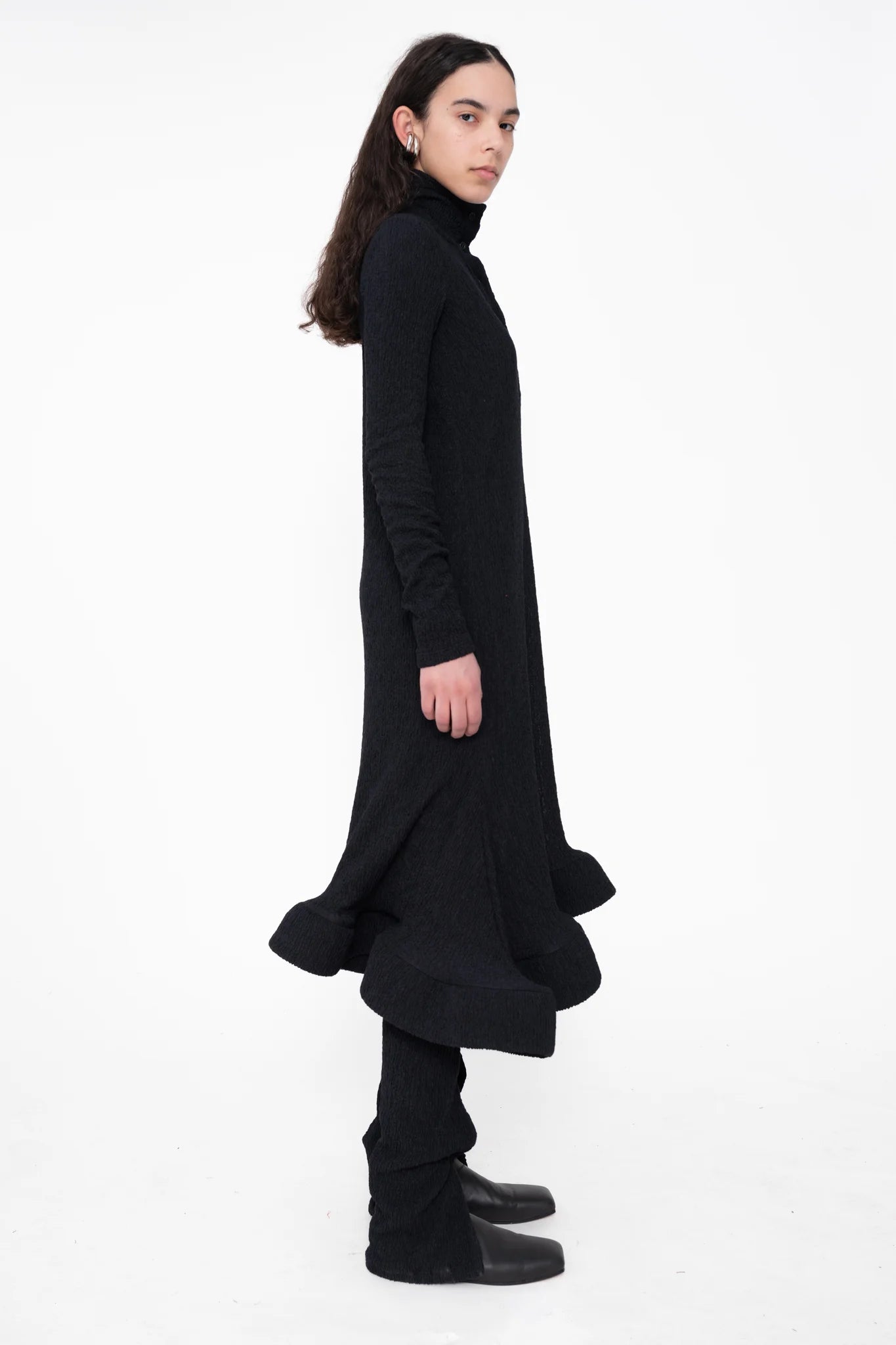 female-wearing-black-longsleeve-midi-dress-with-wavy-hem-and-button-closure-on-white-background-full-body-side