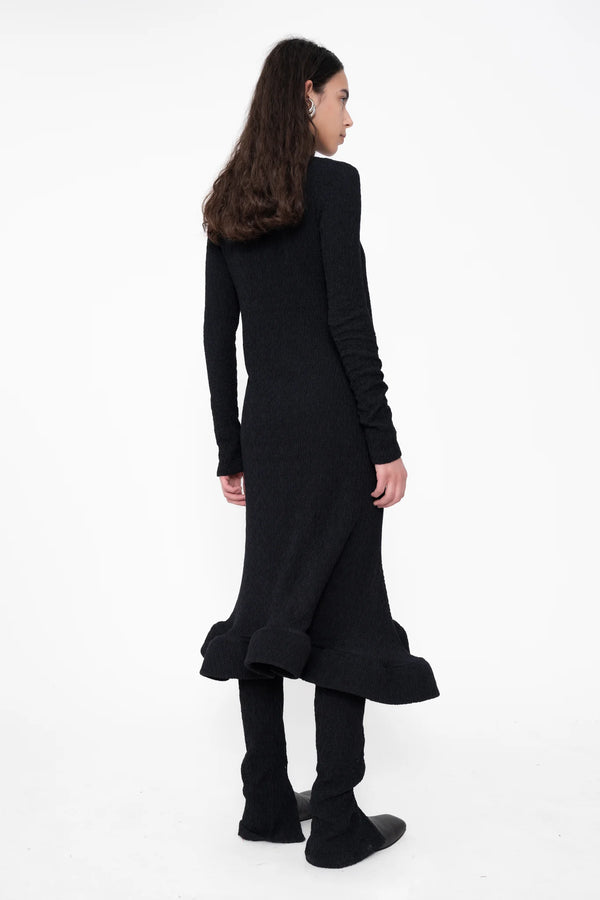 female-wearing-black-longsleeve-midi-dress-with-wavy-hem-and-button-closure-on-white-background-full-body-back-side