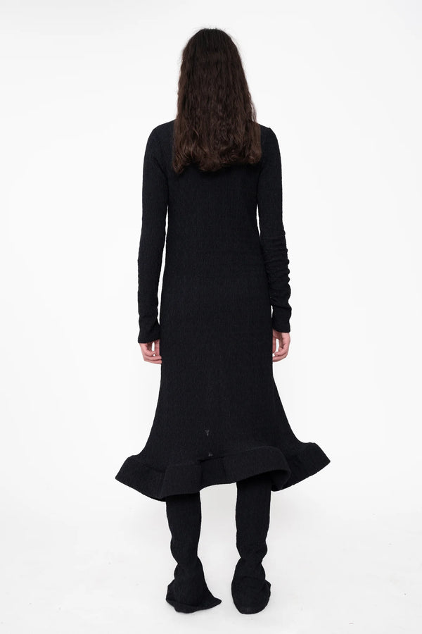 female-wearing-black-longsleeve-midi-dress-with-wavy-hem-and-button-closure-on-white-background-full-body-back