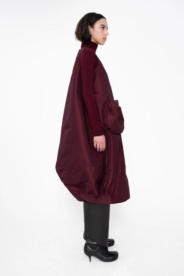 female-wearing-bordeaux-bomber-dress-with-big-front-pocket-on-white-background-full-body-side