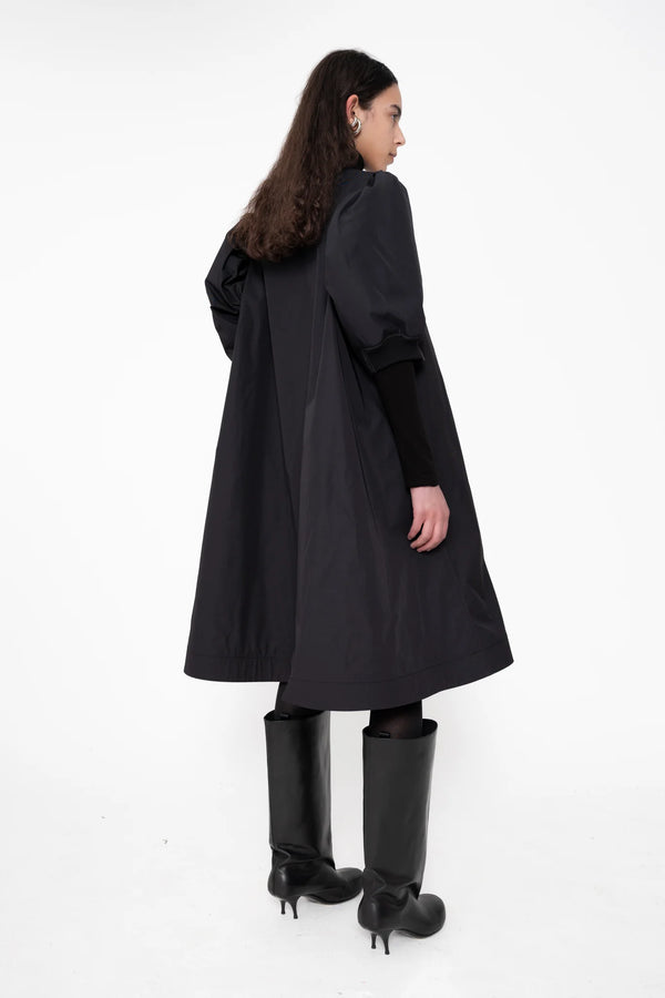 female-wearing-black-bomber-dress-with-zip-and-puffed-cropped-sleeves-and-double-heel-boots-on-white-background-full-body-back-side
