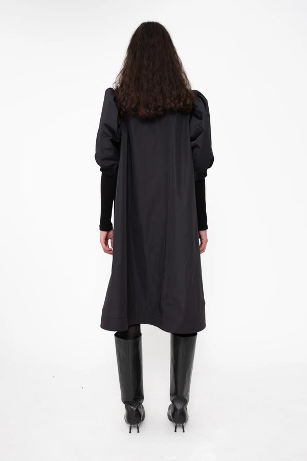 female-wearing-black-bomber-dress-with-zip-and-puffed-cropped-sleeves-and-double-heel-boots-on-white-background-full-body-back
