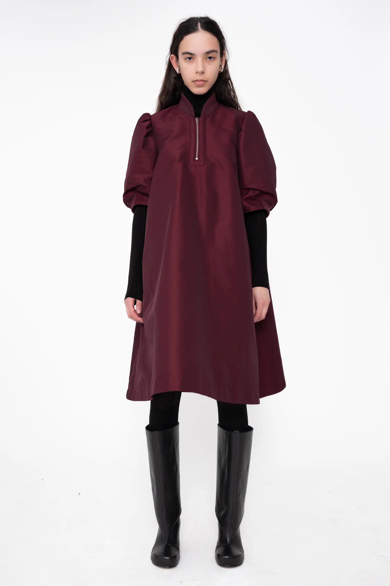 female-wearing-bordeaux-midi-bomber-dress-with-zip-and-cropped-puffed-sleeves-with-black-underlayer-and-boots-on-white-background-full-body-front