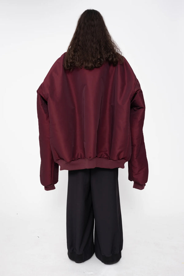 female-wearing-oversized-bordeaux-bomber-jacket-with-slits-at-armholes-and-black-underlayer-top-with-black-suit-pants-on-white-background-full-body-back