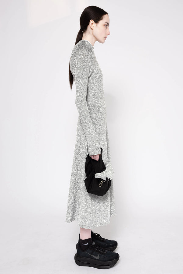 Model wearing silver column dress on a white background, side.