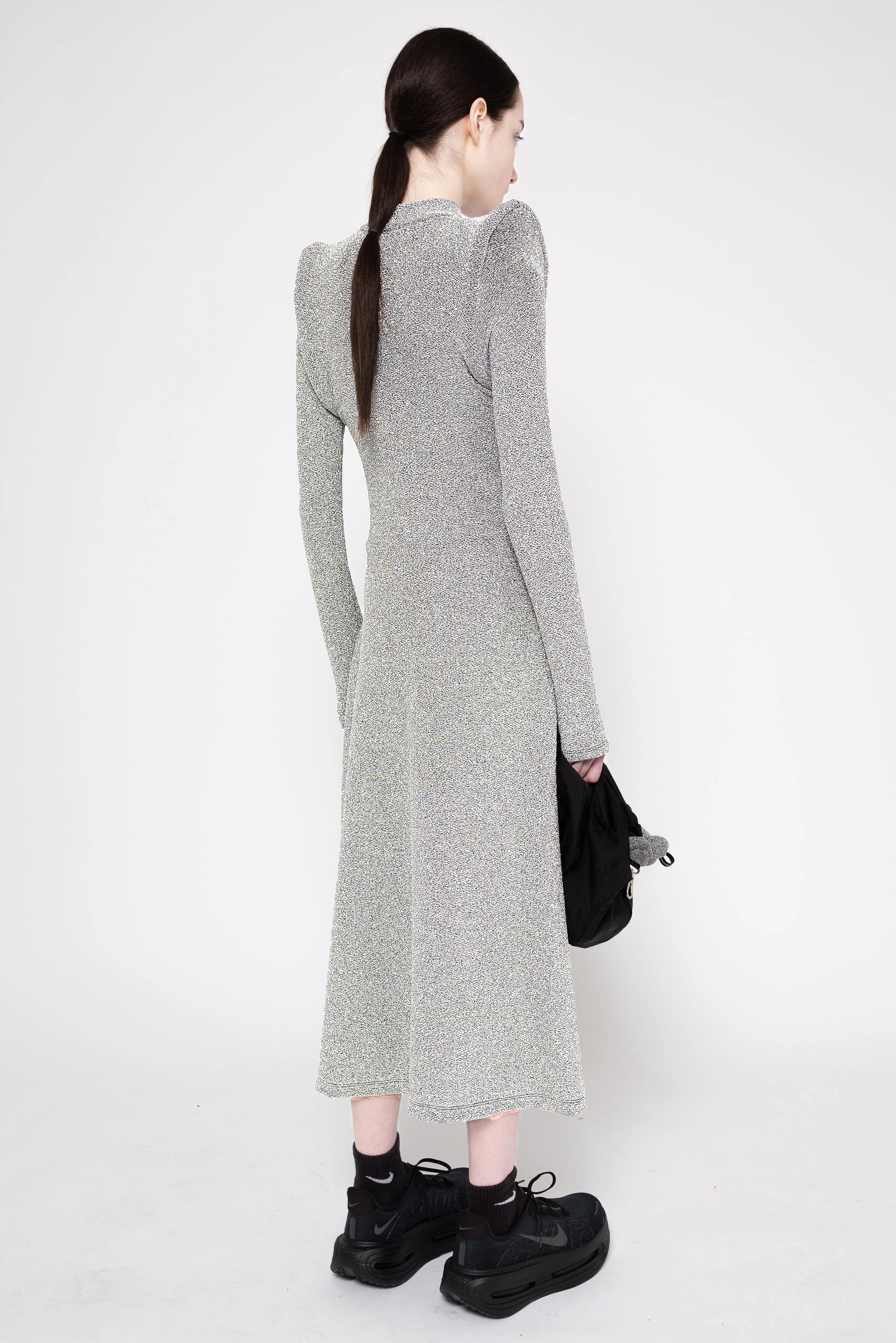 Model wearing silver column dress on a white background, 3/4 back.