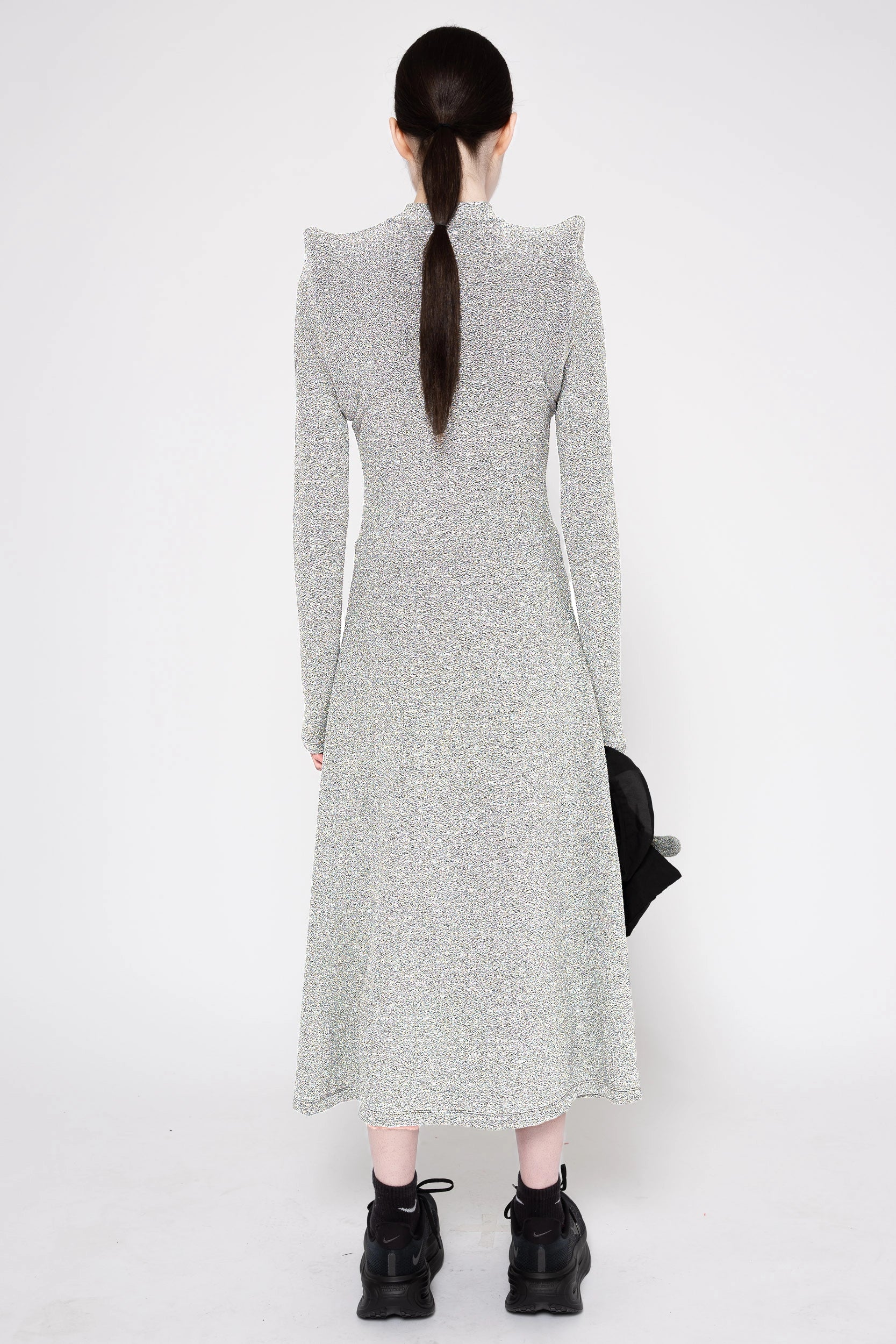 Model wearing silver column dress on a white background, back.