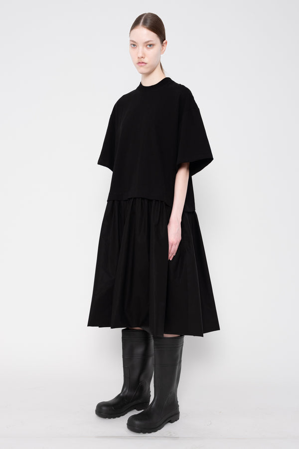 Person wearing a black dress and boots on a white background