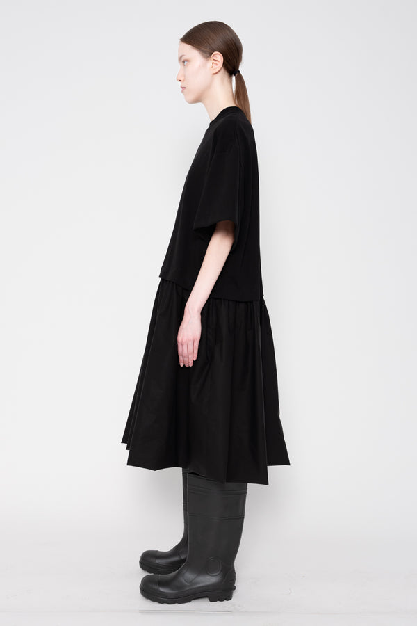 Person wearing a black dress and black boots on a white background