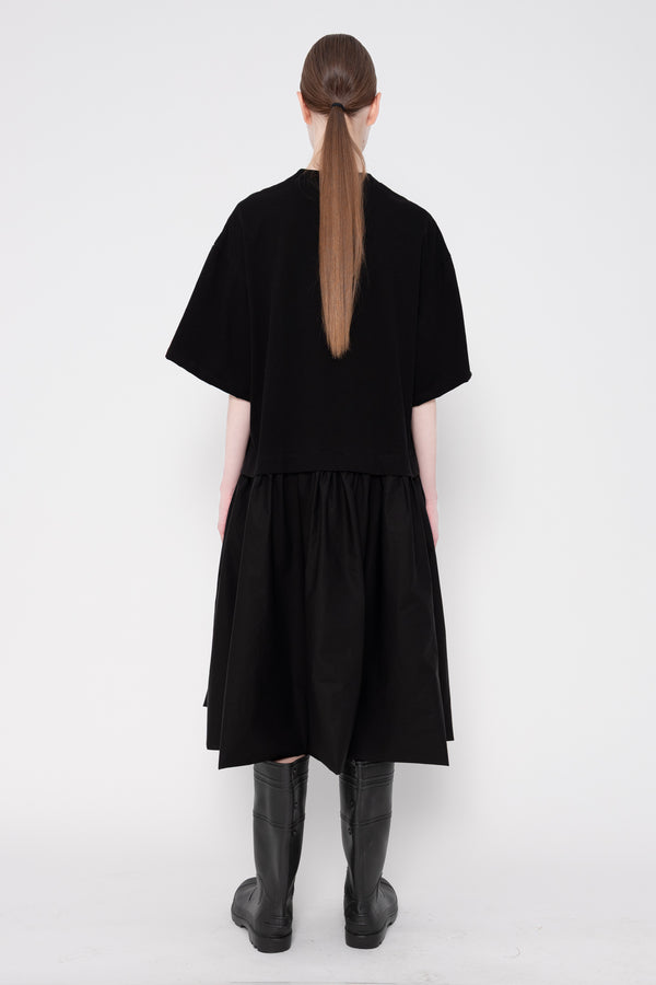 Person wearing a black dress with a plain white background