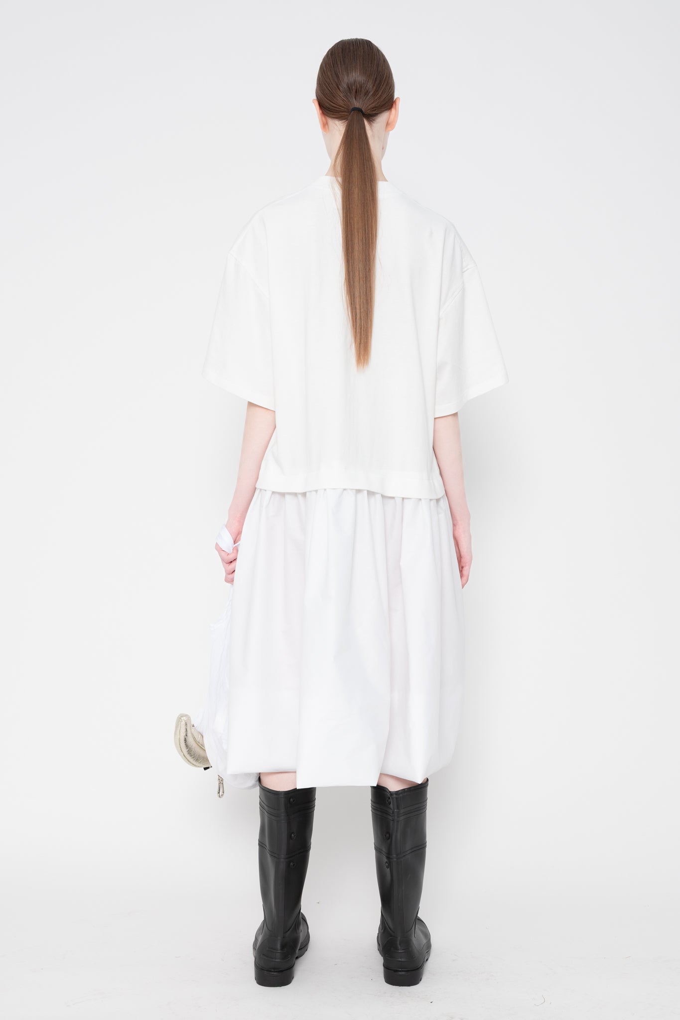 Person wearing a white dress with black boots on a white background