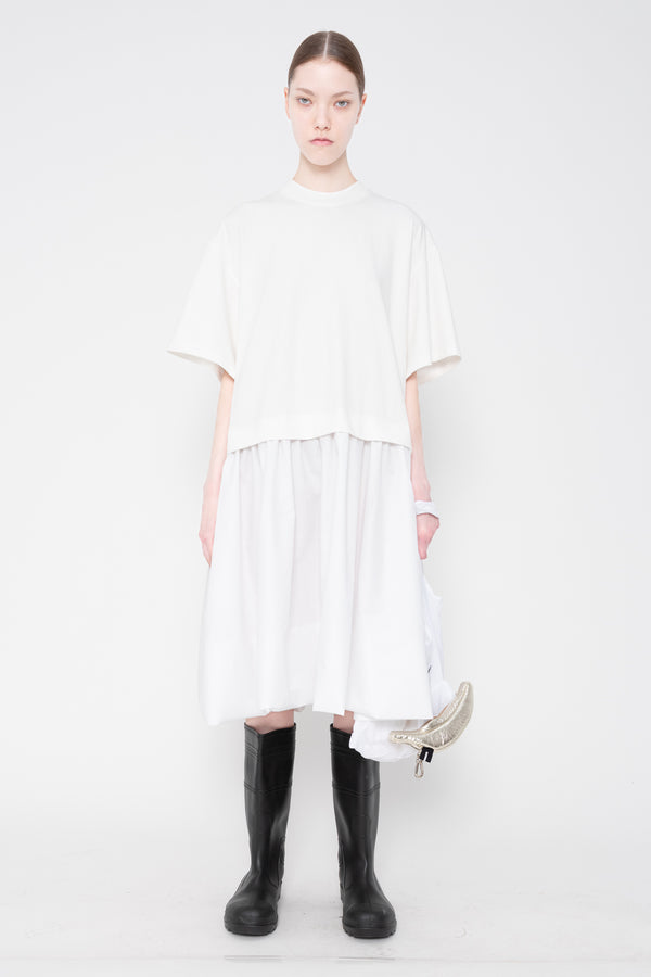 Person wearing a white dress with black boots on a white background