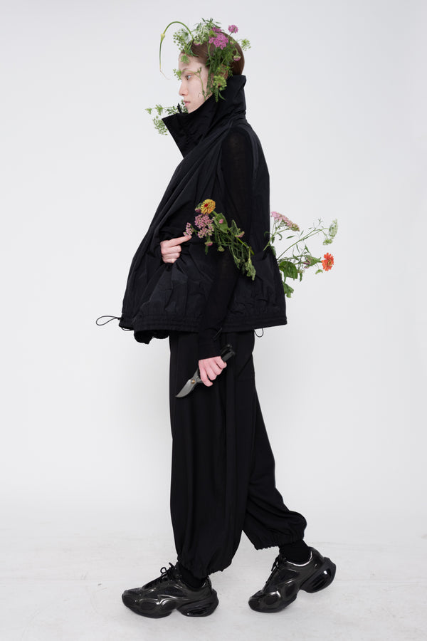 Person wearing a black outfit with flowers and a knife on a white background