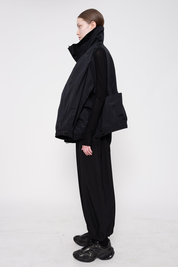 Person wearing a black outfit with a jacket and pants on a white background