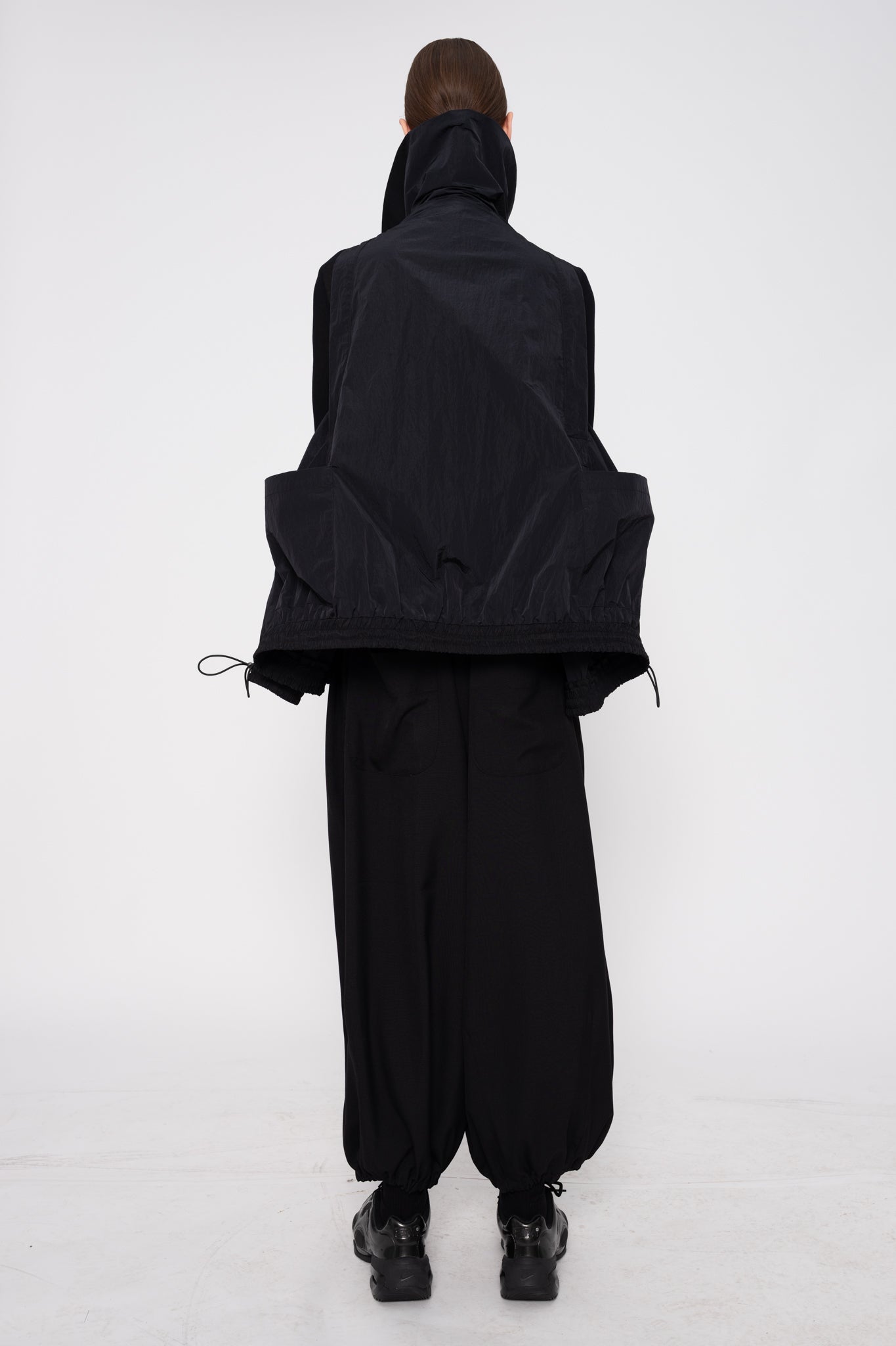 Person wearing a black outfit with a hood on a white background