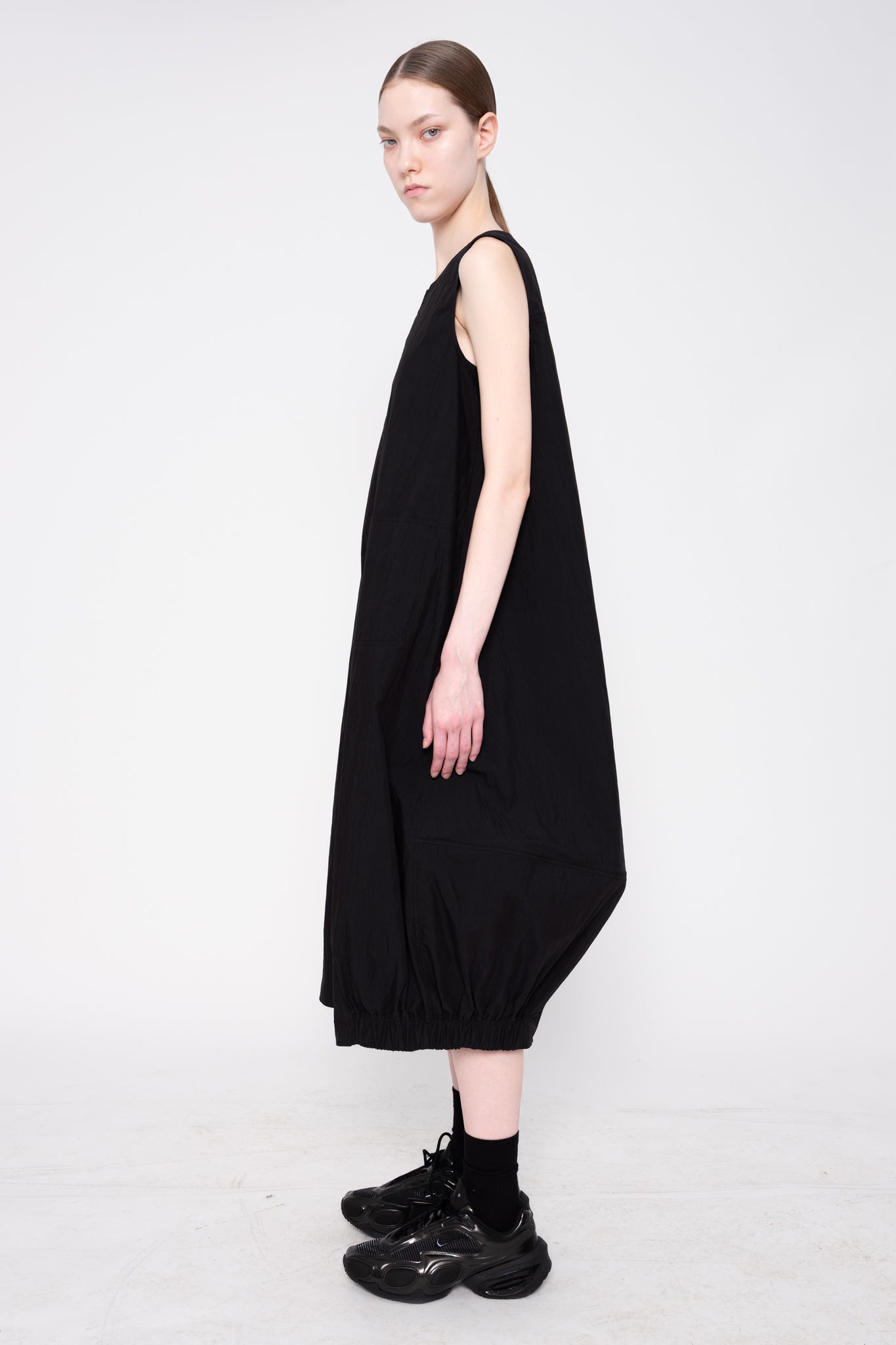 Person wearing a black sleeveless dress on a white background