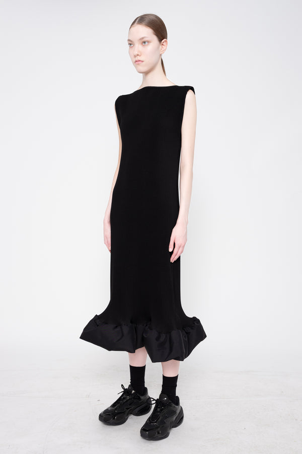 Black dress with ruffled hem worn by a model on a white background