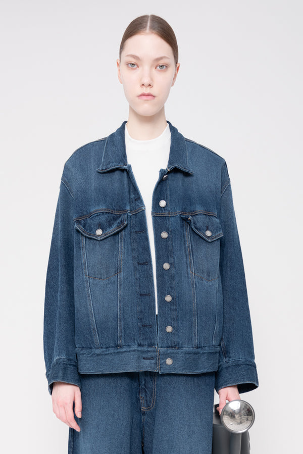 Person wearing a blue denim jacket on a plain background