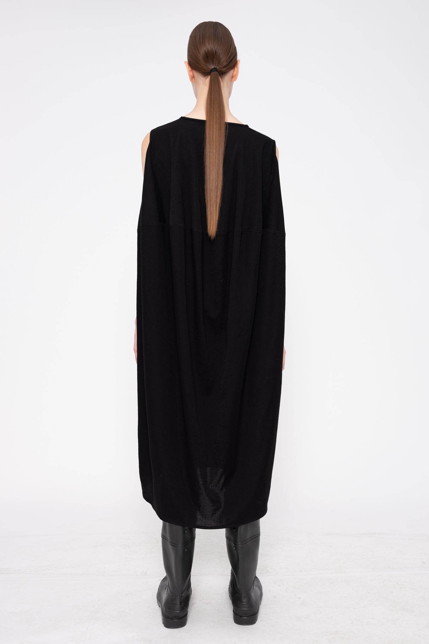 Person wearing a black dress with a slit on a white background