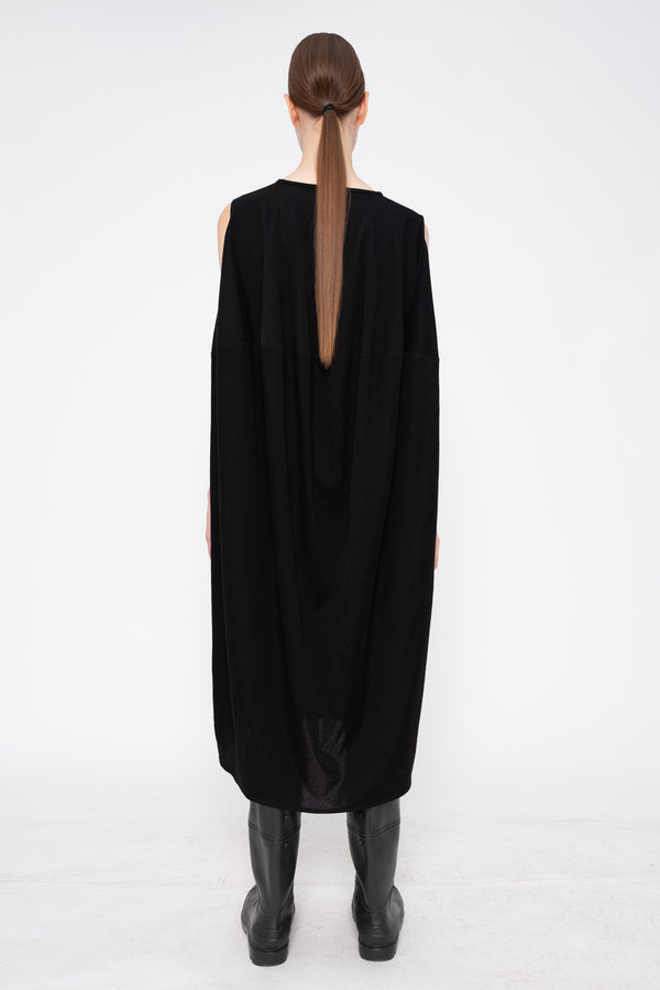 Person wearing a black dress with a slit on a white background