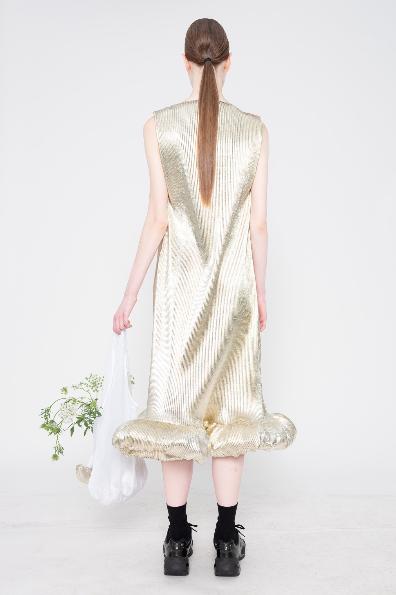Woman wearing a gold sleeveless dress on a white background