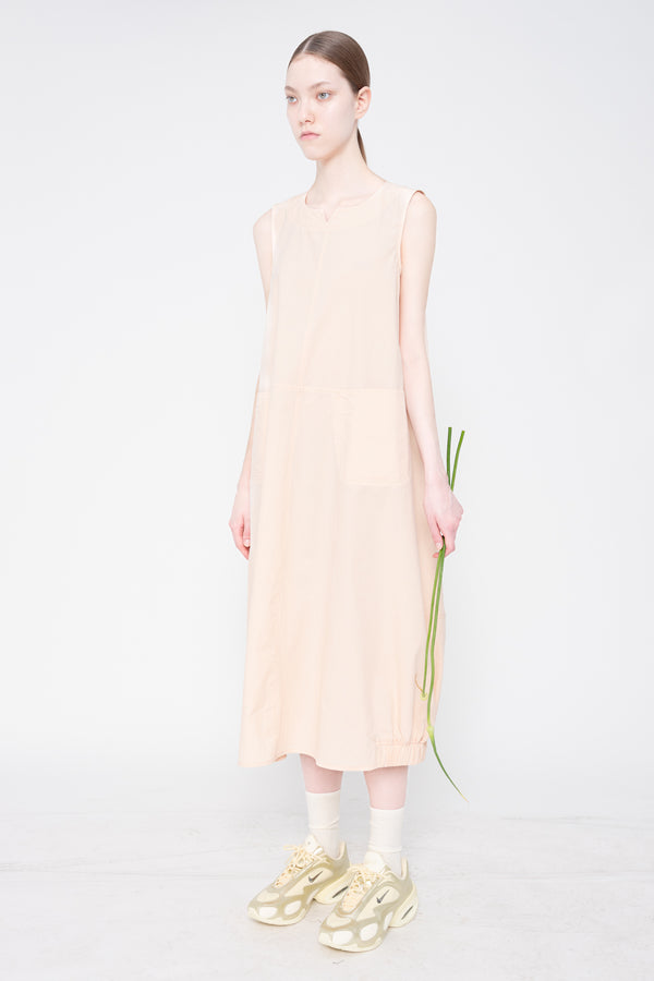 Woman wearing a light pink dress holding a green plant on a white background