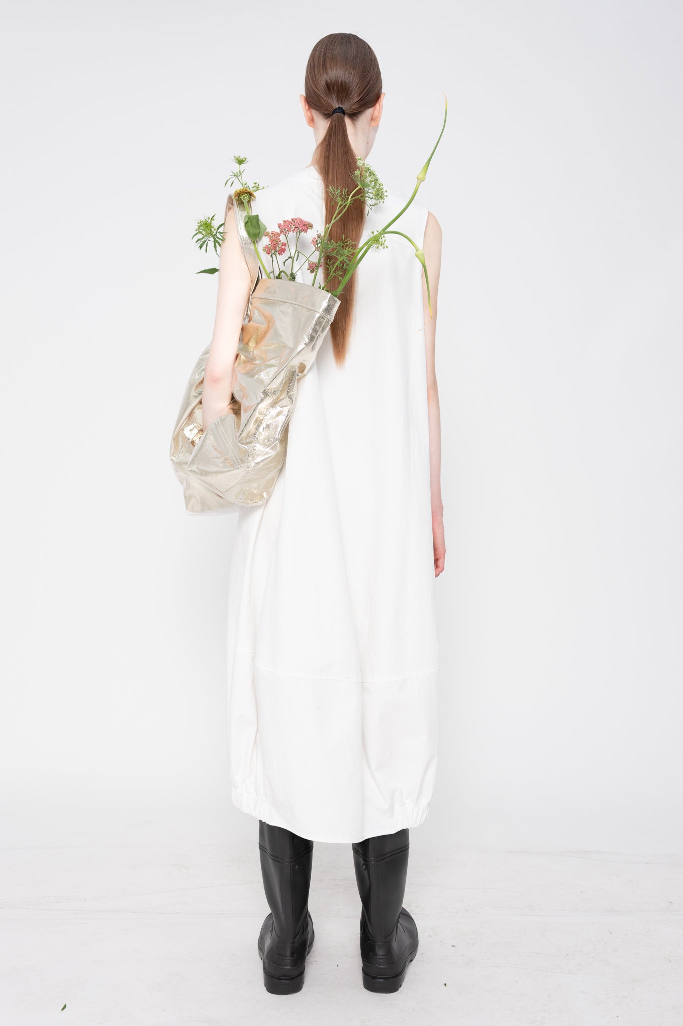 Person wearing a white dress holding flowers against a white background