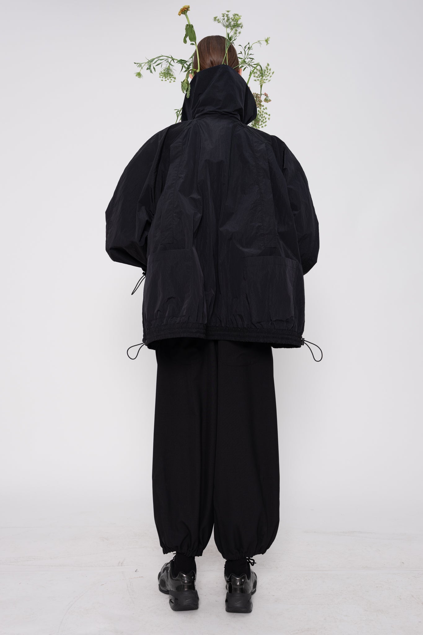 Person wearing a black outfit with a hood on a white background