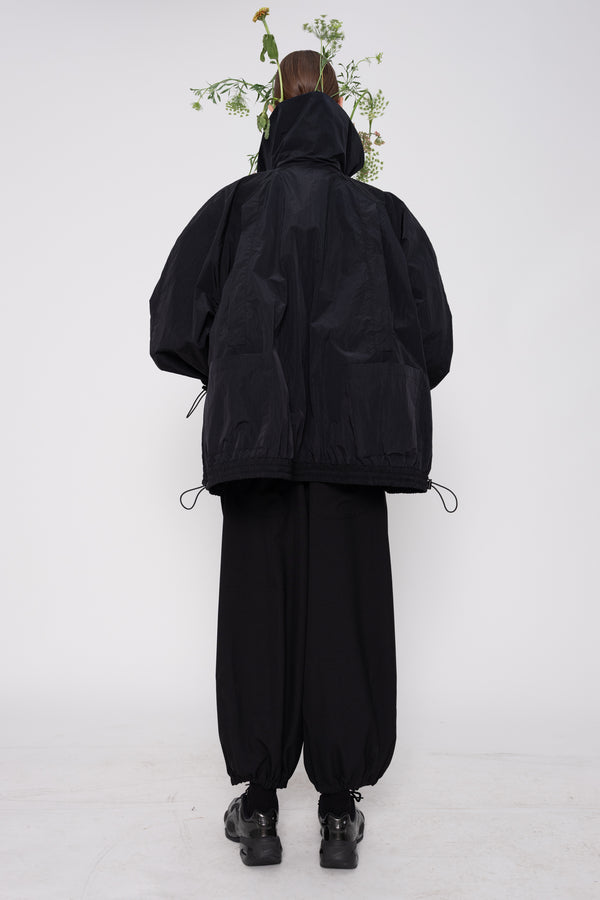 Person wearing a black outfit with a hood on a white background