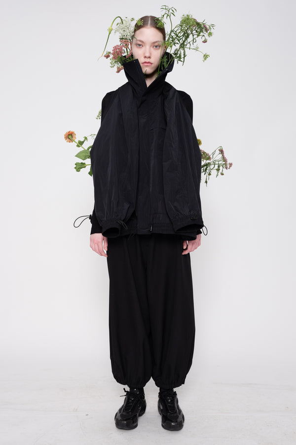 Person wearing a black outfit with a white background and floral decorations.